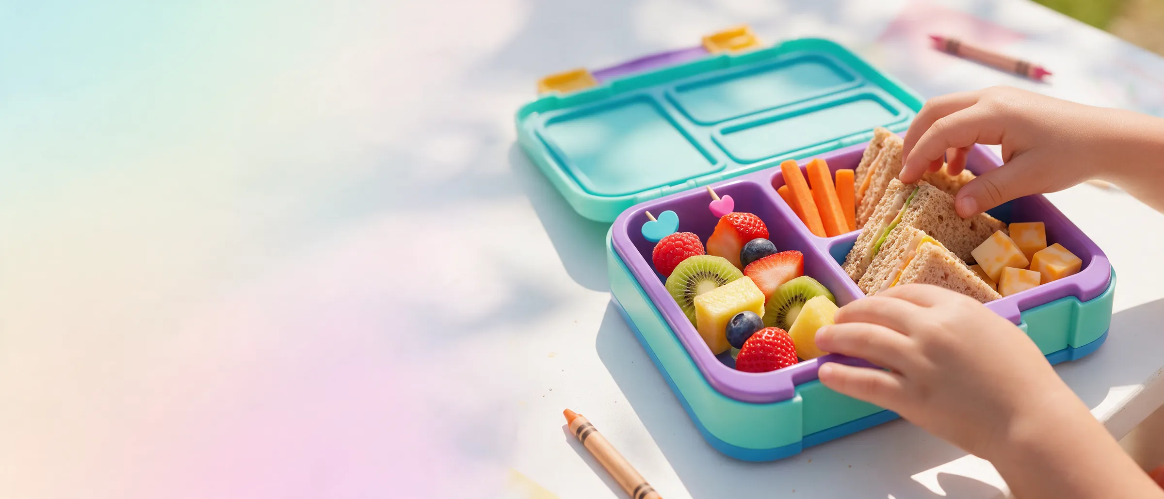 Manos de un niño tomando fruta y verduras de una lonchera de colores